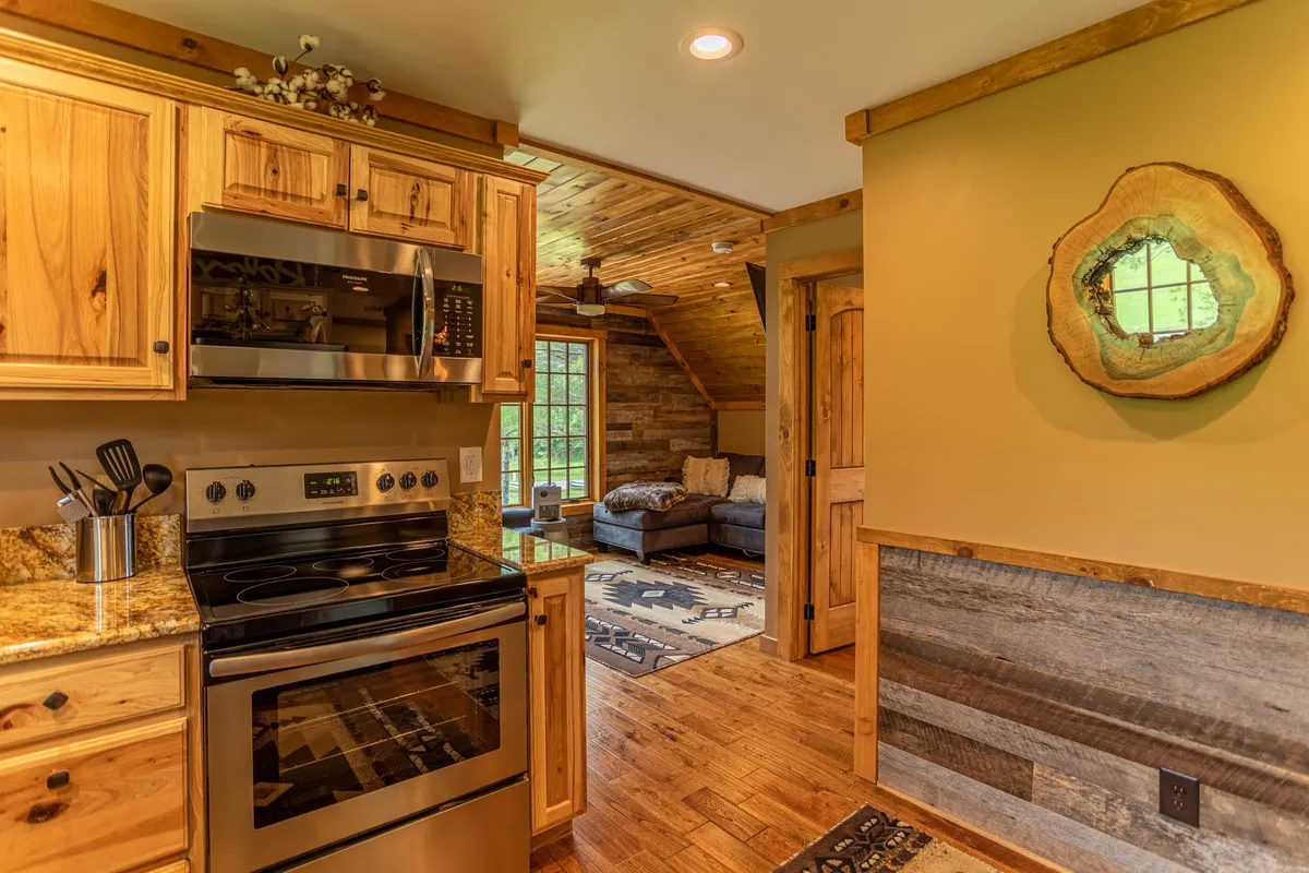 A spacious kitchen and living area with stainless steel appliances, wooden cabinets, a plush couch, and a decorative mirror. The scene feels open, social, and inviting, perfect for gathering after outdoor adventures or festivals.